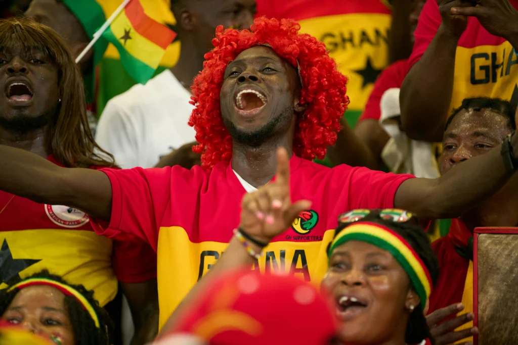 Who Is the Face of Ghana Football – passionate Ghana national team supporters celebrating in Black Stars colours during an international match.