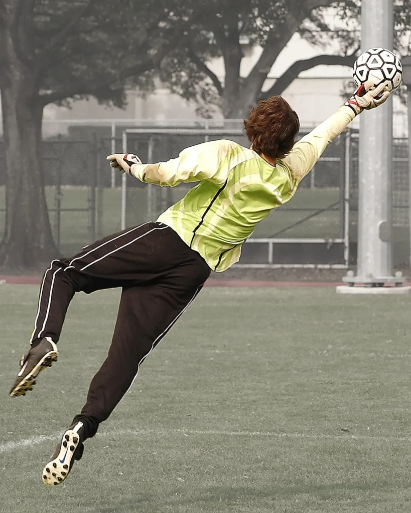 Goalkeeper diving to catch a ball during training, illustrating why flexibility is important in football for quick reactions, full-body reach, and injury prevention.