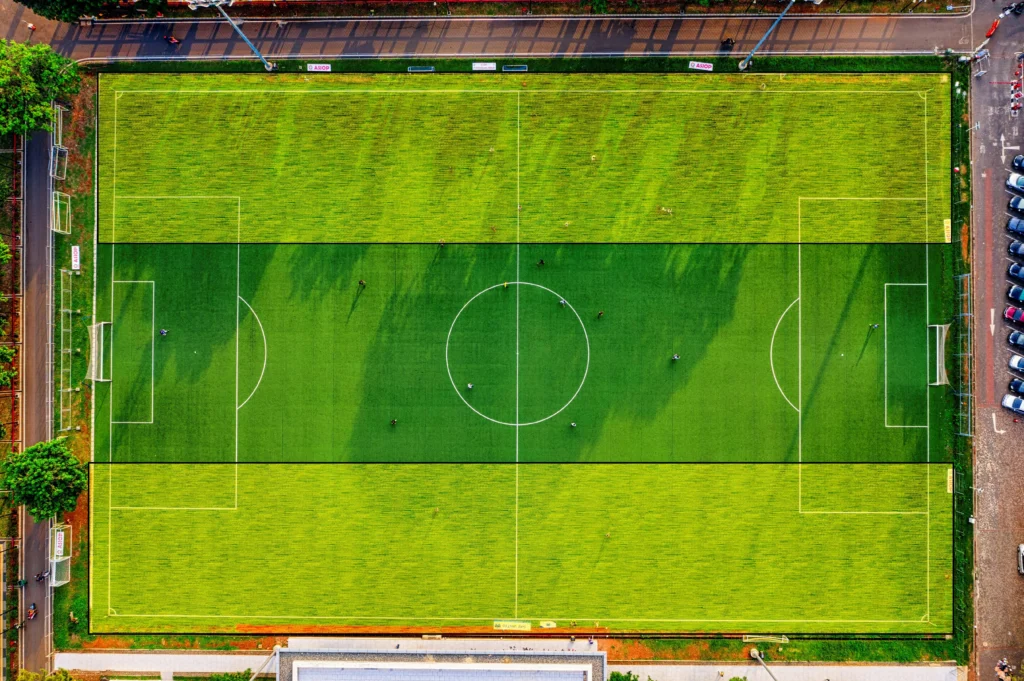 Aerial view of a football pitch with the wide areas along both sides highlighted, illustrating the flanks in football and how teams use these wing spaces to create attacks and stretch the opposition defense.