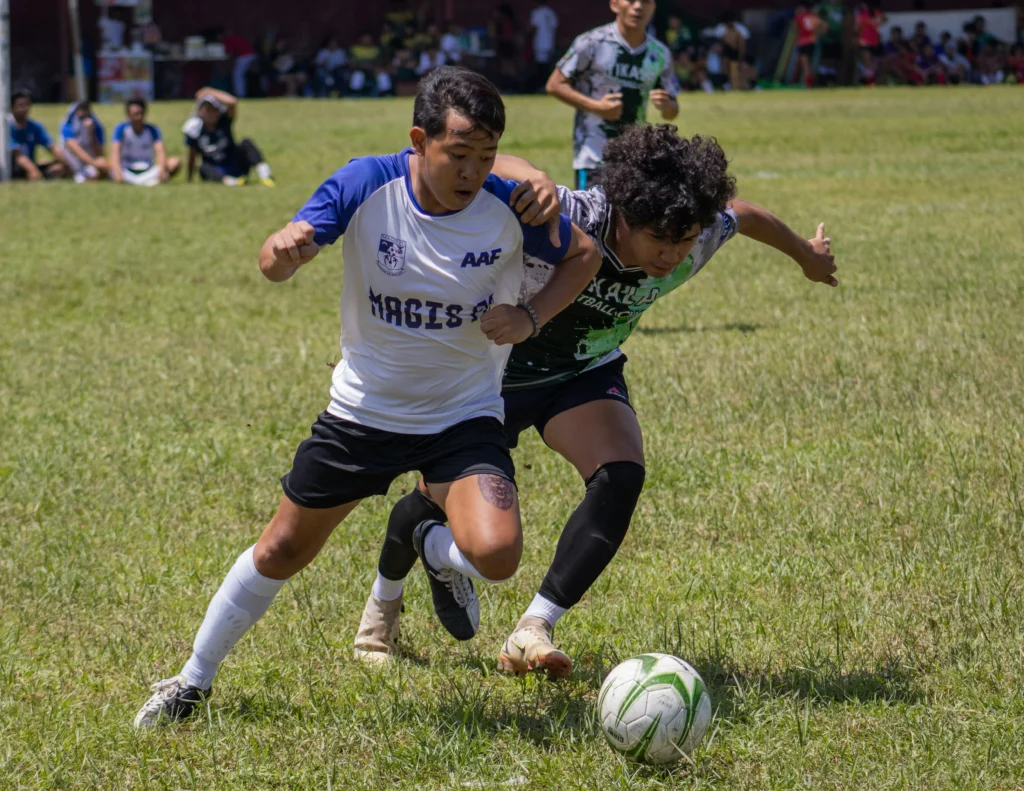 A football player shielding the ball from a defender, showcasing the lower-body power and stability needed to maintain possession.