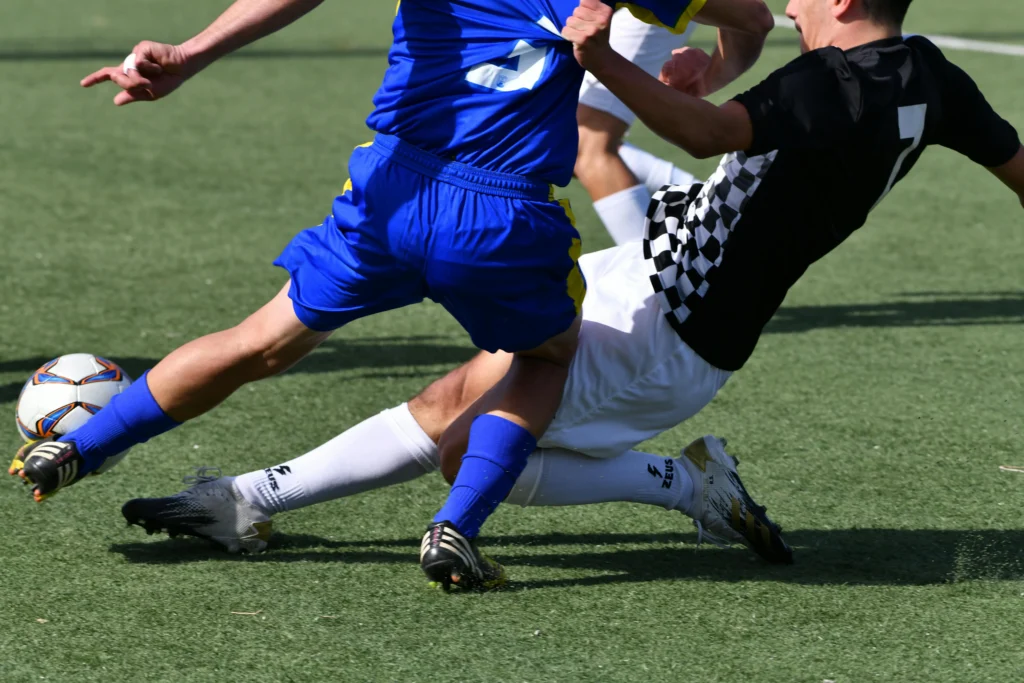 Football defender performing a slide tackle to win the ball from an opponent, illustrating how to tackle in football using proper timing, balance, and technique.